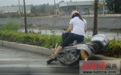 风疾雨劲,路上一骑摩托车女子途中摔倒